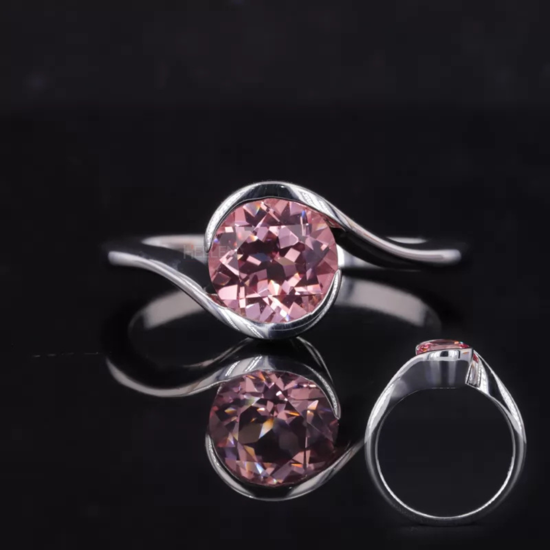 Pink sapphire solitaire ring with round cut center and twisted band – unique and artistic engagement design