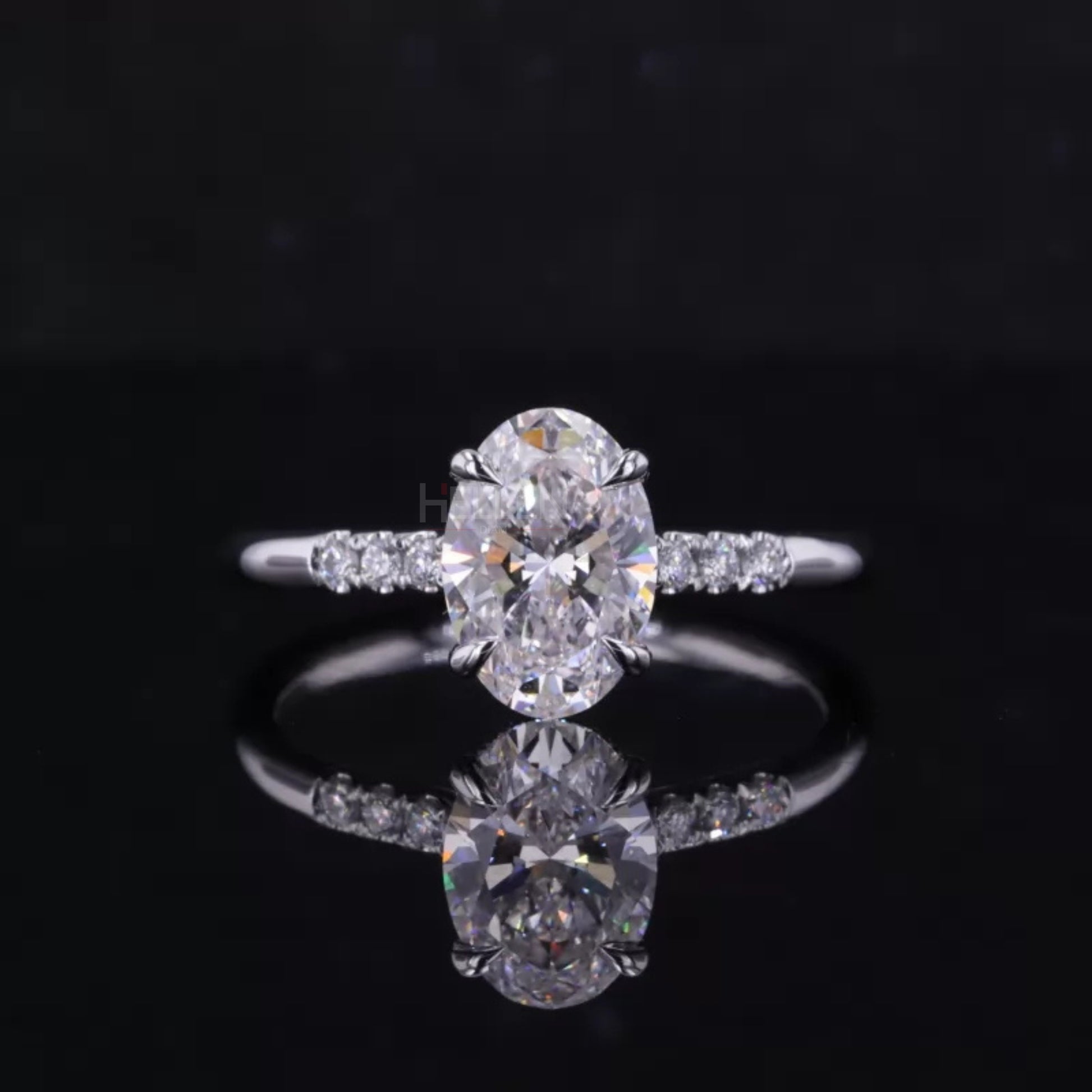 Oval cut moissanite solitaire ring with round side stones in claw prong setting – elegant three-stone engagement design