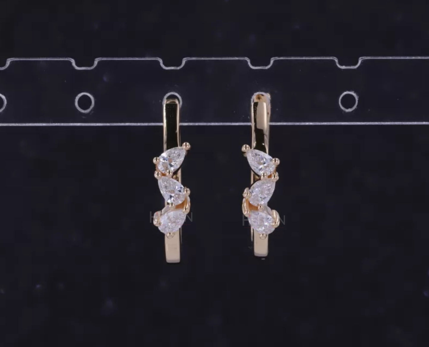 Hoop earrings with three-stone setting and pear cut solitaire – modern elegance with dynamic design